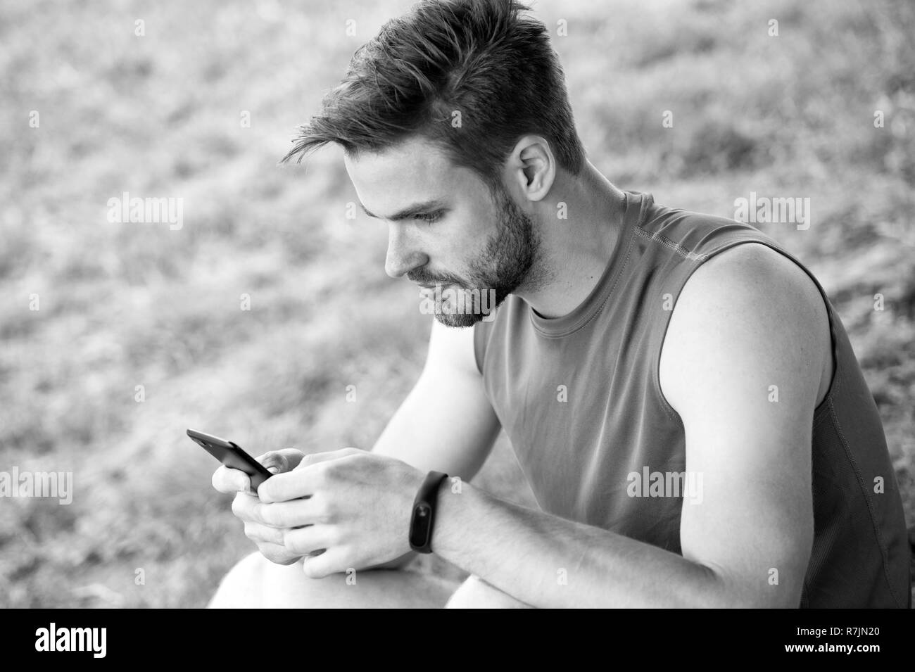 Restez en ligne et disponibles. Sms texte sportif sur l'air frais. L'homme se détendre avec le smartphone sur l'herbe verte. L'activité d'été. Toujours en contact. Technologies rendent plus facile la formation. Sport blog et weblog. Banque D'Images