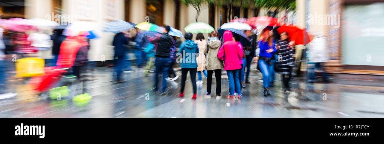 Photo avec l'appareil photo fait effet de zoom de personnes avec des parasols autour de la ville des pluies Banque D'Images