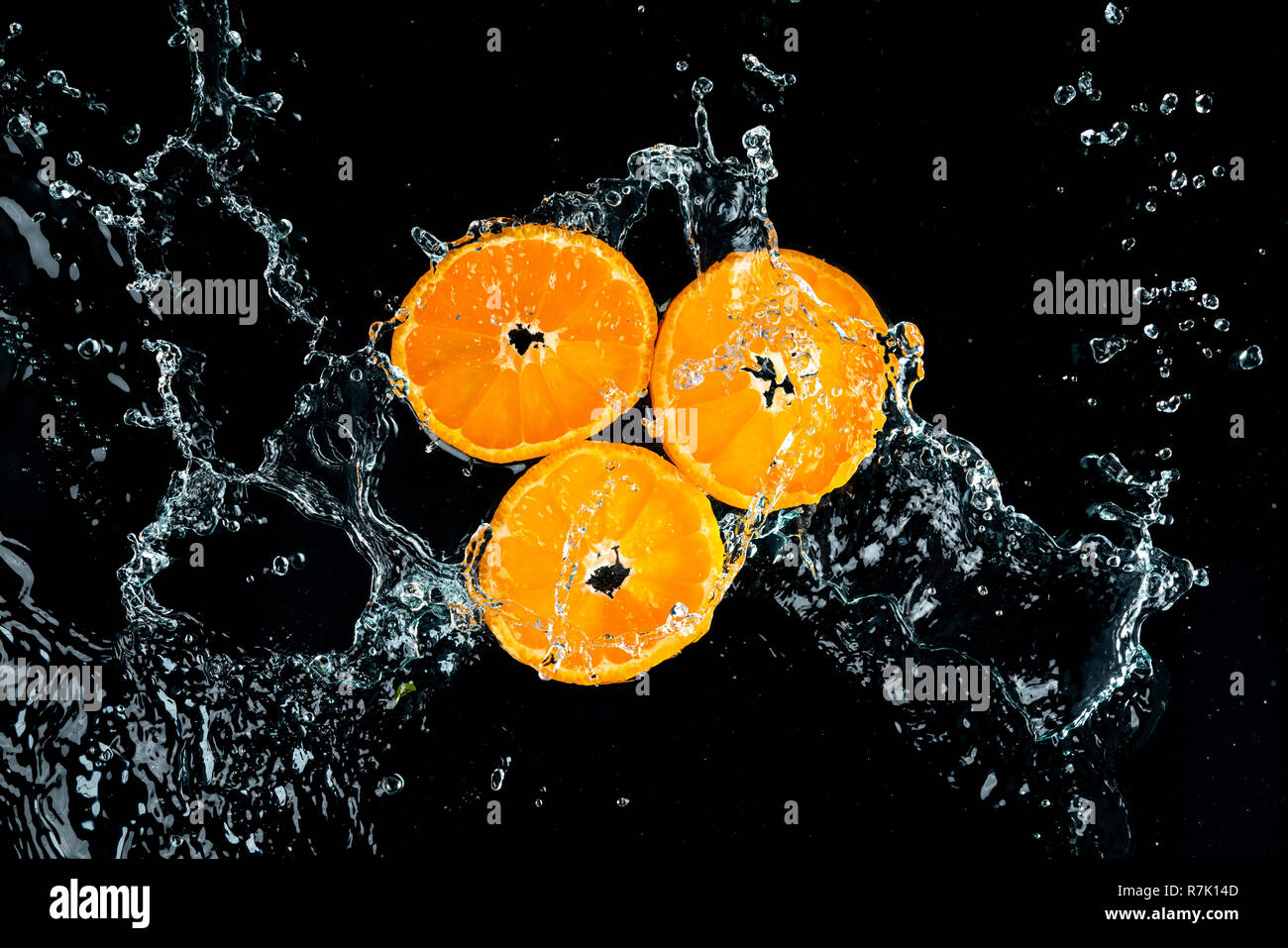 Les oranges, les éclaboussures d'eau sur fond noir Banque D'Images