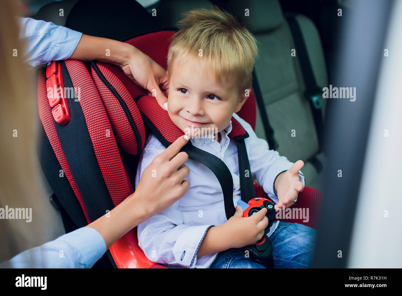 Bebe Garcon Avec Des Cheveux Boucles Assis Dans Un Siege D Auto Pour Enfant Avec Petite Voiture En Mains Photo Stock Alamy