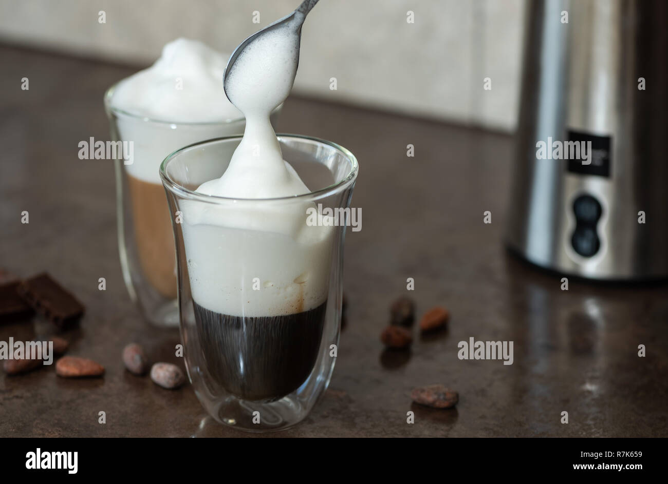 Mousse de lait est mis dans un verre de café. Banque D'Images