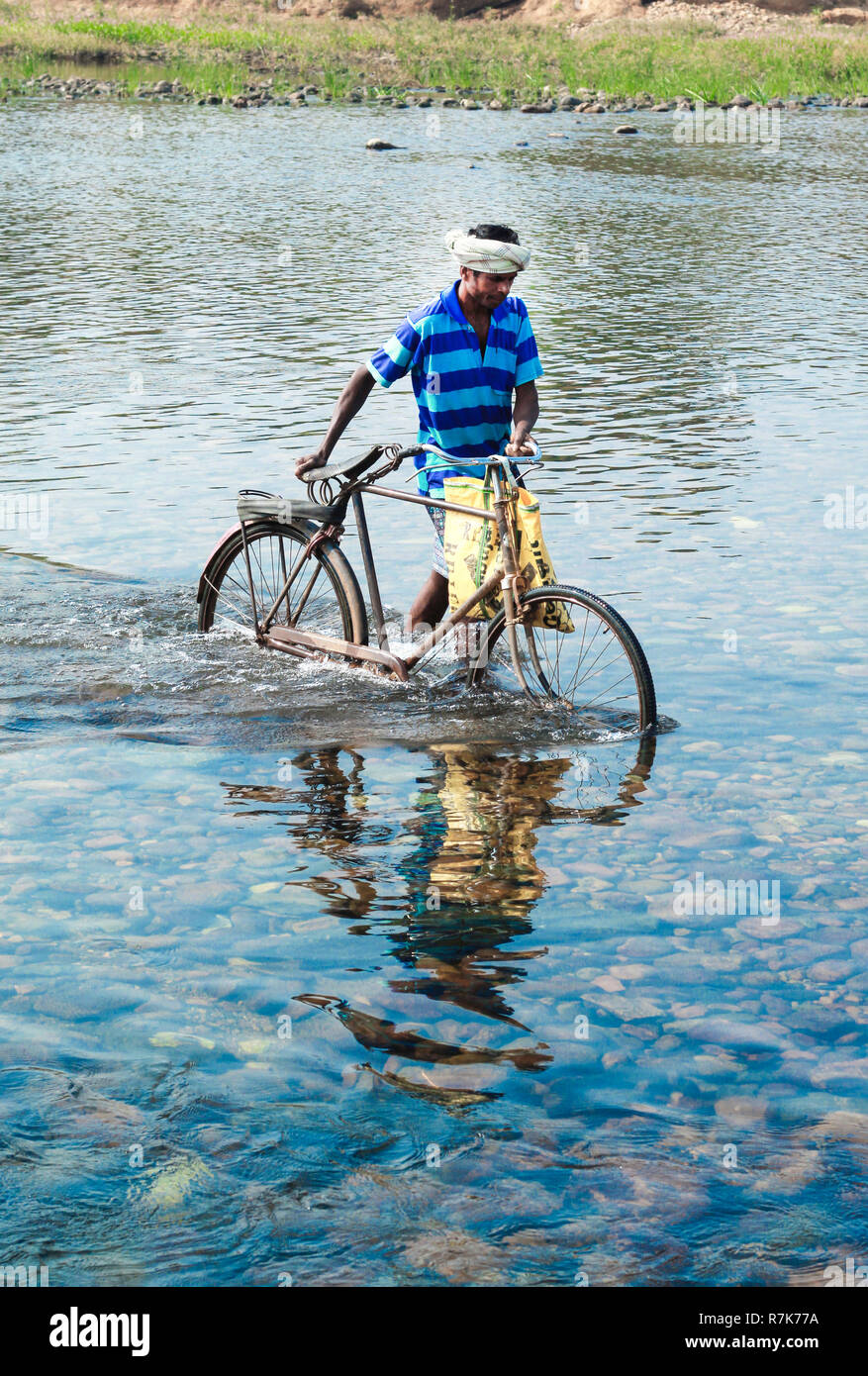 L'homme de village traversé rivière avec son vélo Banque D'Images