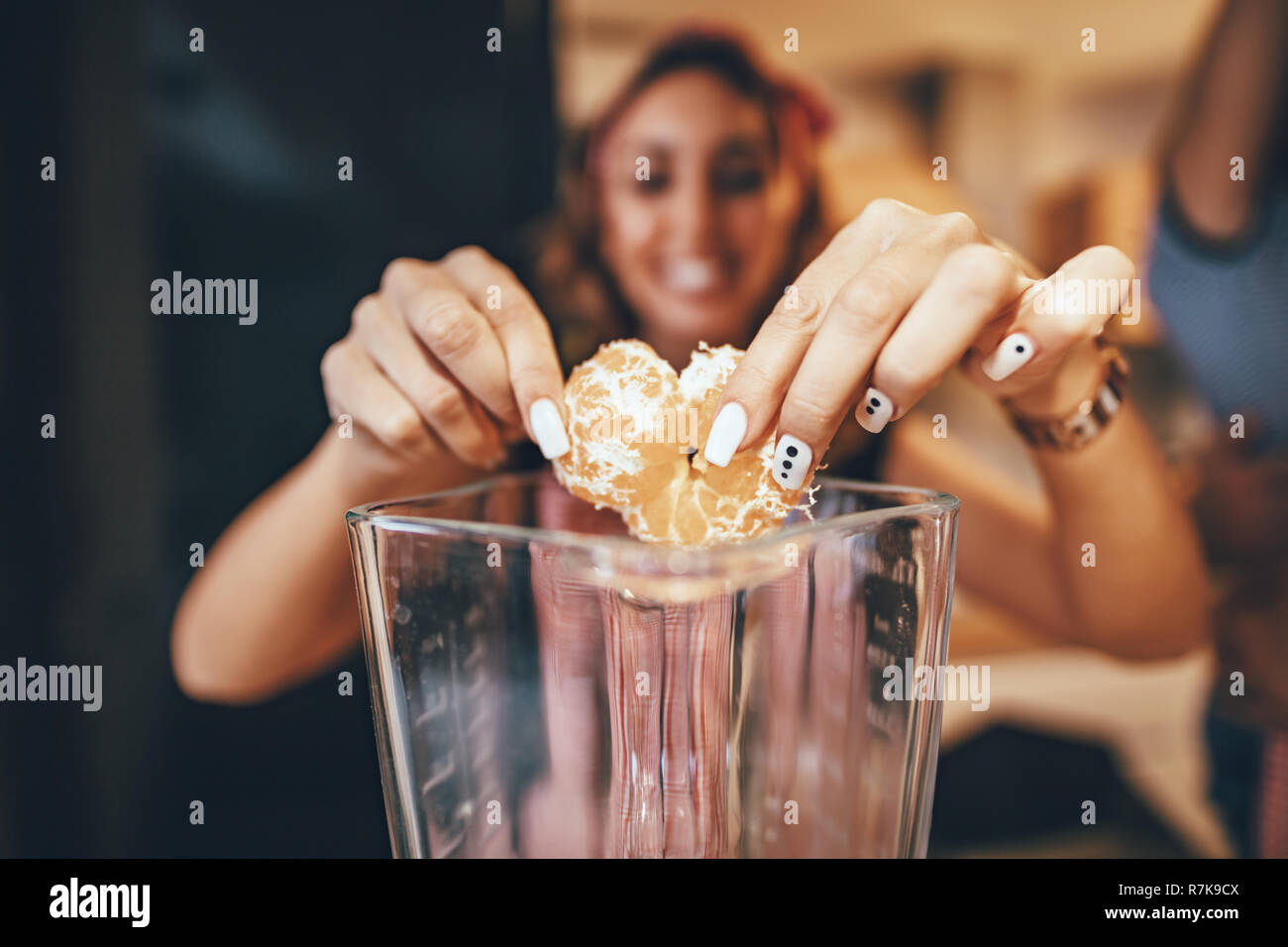 Jeune femme prépare repas sain dans la cuisine. Elle se met dans le mixer les tranches de mandarine. Banque D'Images