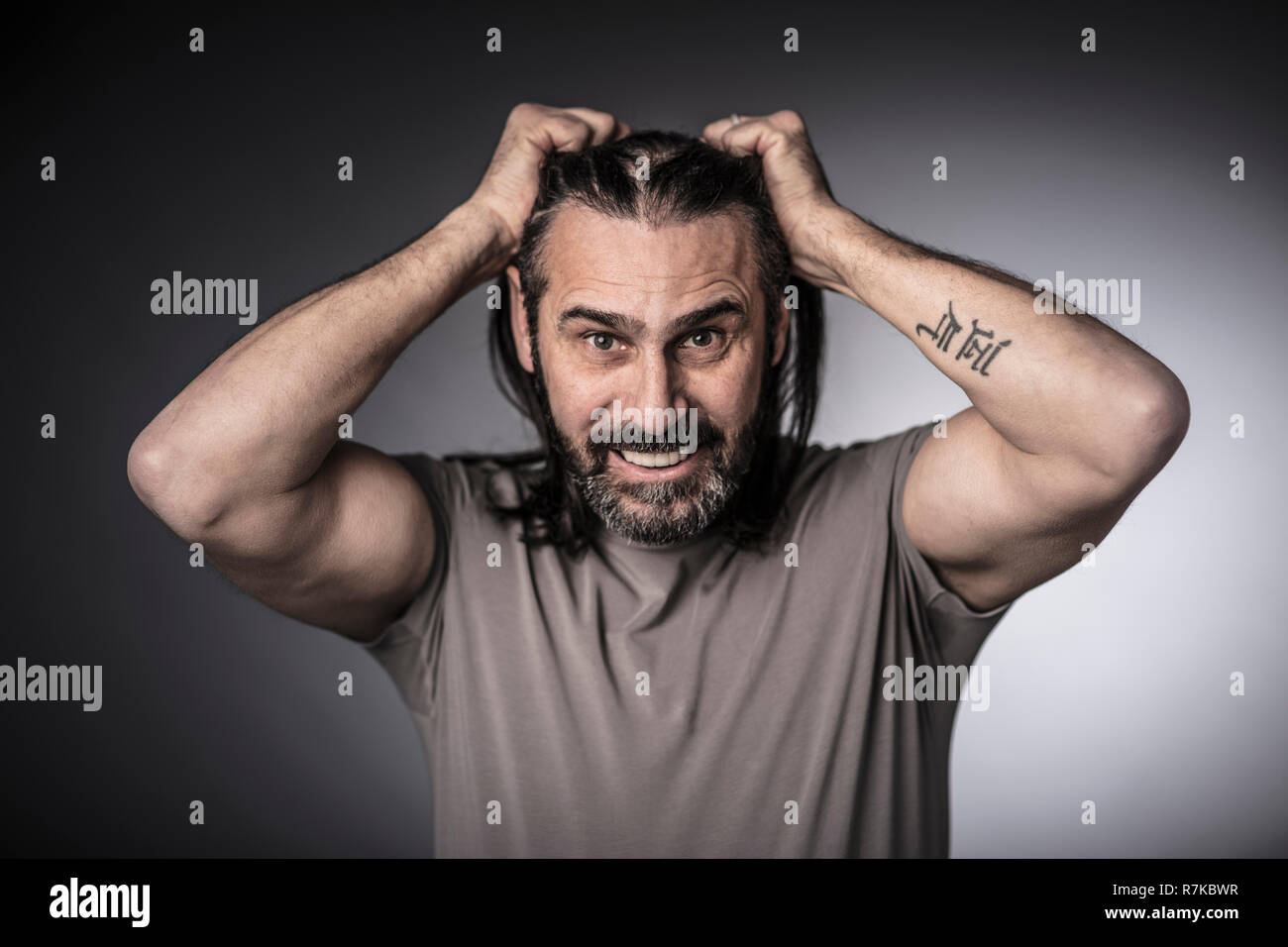Homme tenir ses longs cheveux avec les mains, studio shot Banque D'Images