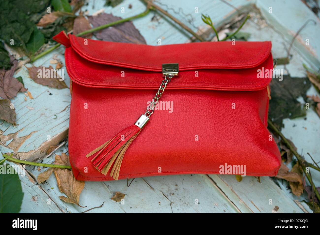Embrayage - petit sac à main rouge sur un fond de bois sur un fond avec des  feuilles Photo Stock - Alamy