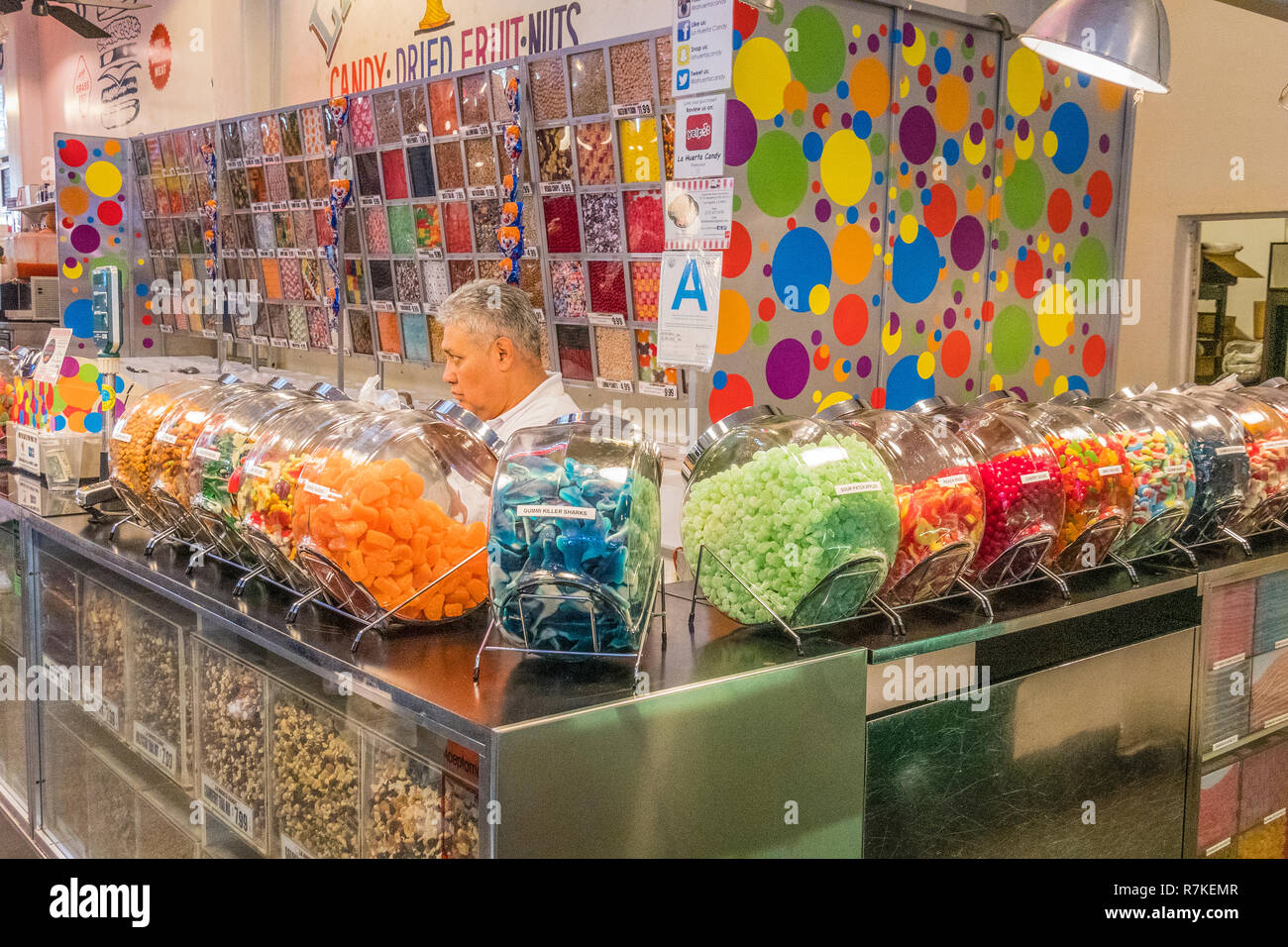 Le propriétaire du magasin se tient derrière une longue rangée de bocaux en verre remplis de bonbons de divers types de bonbons à vendre dans son magasin à l'intérieur du Grand Marché Central Banque D'Images
