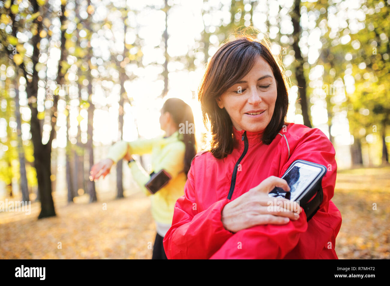 Dames avec le smartphone à l'extérieur dans la forêt dans la nature, la mesure du temps. Banque D'Images