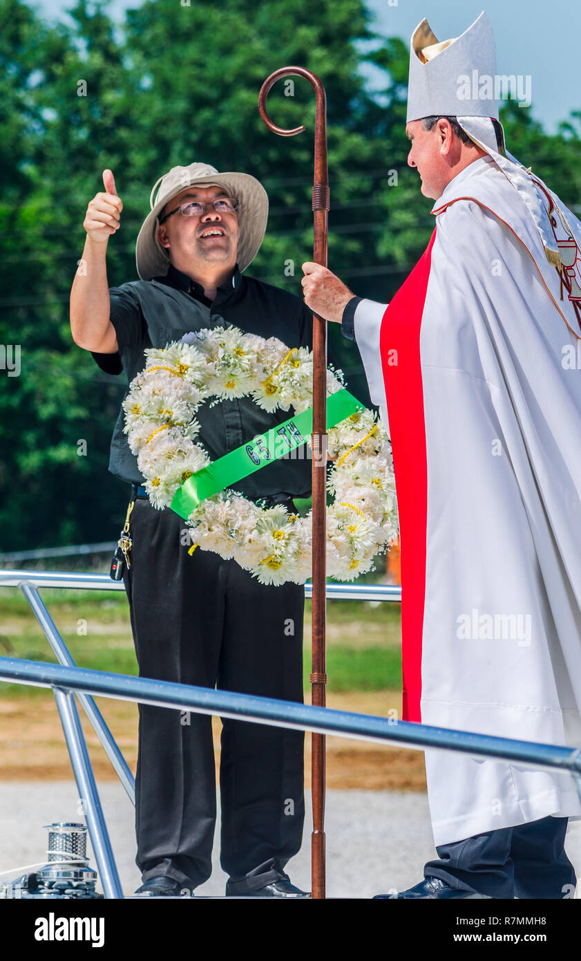 Le Révérend Nguyen Bieu tient une couronne de cérémonie comme il parle d'un archevêque catholique Thomas J. Rodi à la bénédiction de la flotte à Bayou La Batre, Alabama. Banque D'Images
