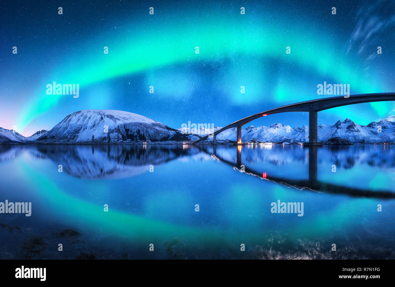 Pont et aurore boréale sur les montagnes enneigées. Les îles Lofoten, Norvège. Amazing northern lights et de réflexion dans l'eau. Paysage d'hiver avec Starr Banque D'Images