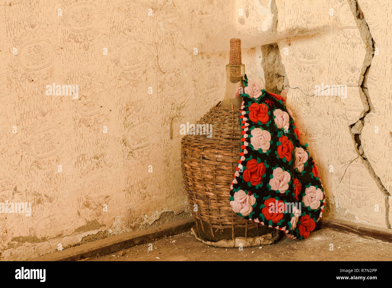 Une grande bouteille de vin vieux dans panier en osier recouvert d'un sac ethnique. Banque D'Images