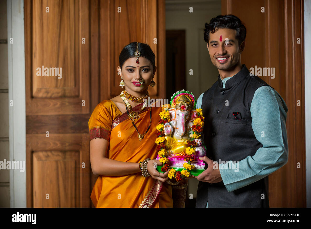 Couple Maharashtrian en vêtements traditionnels célébrant festival ganapati tenant une petite statue de seigneur ganesha ensemble. Banque D'Images