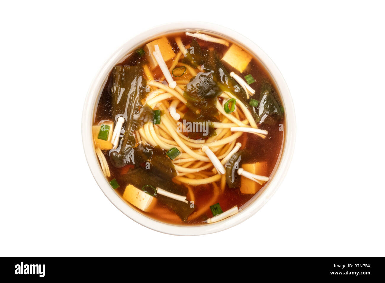 Une photo d'un bol de soupe miso avec le tofu, les oignons verts, les nouilles, les champignons Enoki et wakame, tourné à partir du haut, isolé sur un fond blanc avec une cl Banque D'Images