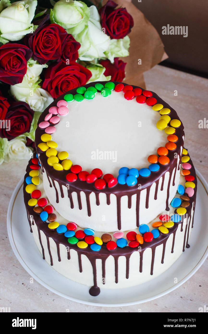Gâteau d'anniversaire blanche colorée avec plus de Sprinkles un fond clair avec un bouquet de roses. Banque D'Images