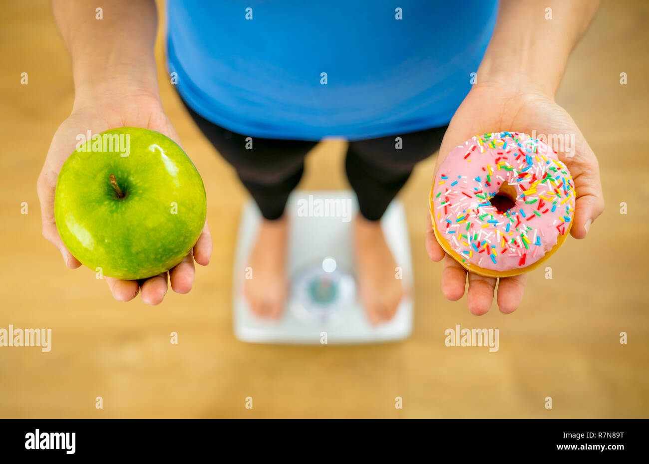 Close up of woman holding sur échelle sur les mains et faire des choix d'apple de beignes entre la santé des aliments malsains dessert pendant la mesure de poids de corps dans l'écrou Banque D'Images