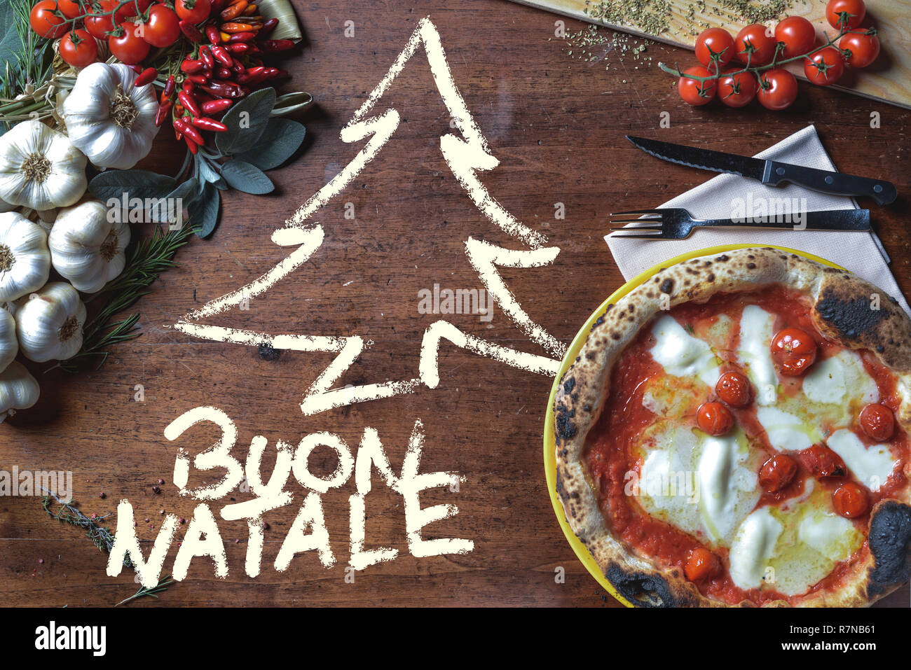 Wroten Italien Buon Natale sur le dessus du châssis sur la table de Noël avec la pizza Margherita, l'ail et fines herbes Banque D'Images