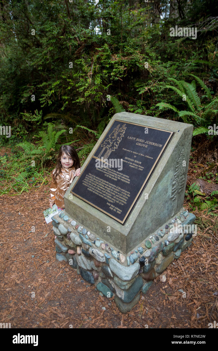 California redwoods National Park, CA - le 20 novembre 2018 : Jeune fille à côté d'un panneau le long de la piste à la Lady Bird Johnson Grove Trail dans la Calif Banque D'Images