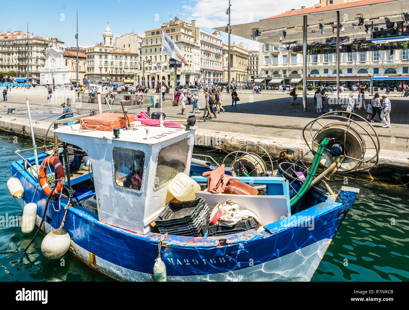 Le Quai des Belges vu depuis le bassin du Vieux Port de Marseille, France, avec un vieux bateau de pêche et le parasol en miroir par Norman Foster. Banque D'Images