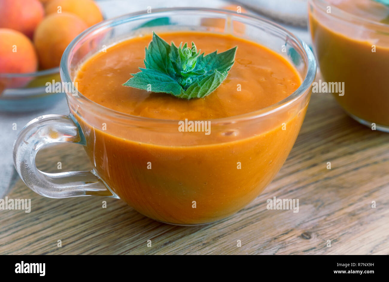 Sur la table dans une tasse en verre de smoothie d'abricots à la menthe pétales. Près de l'ensemble de l'abricot. Banque D'Images