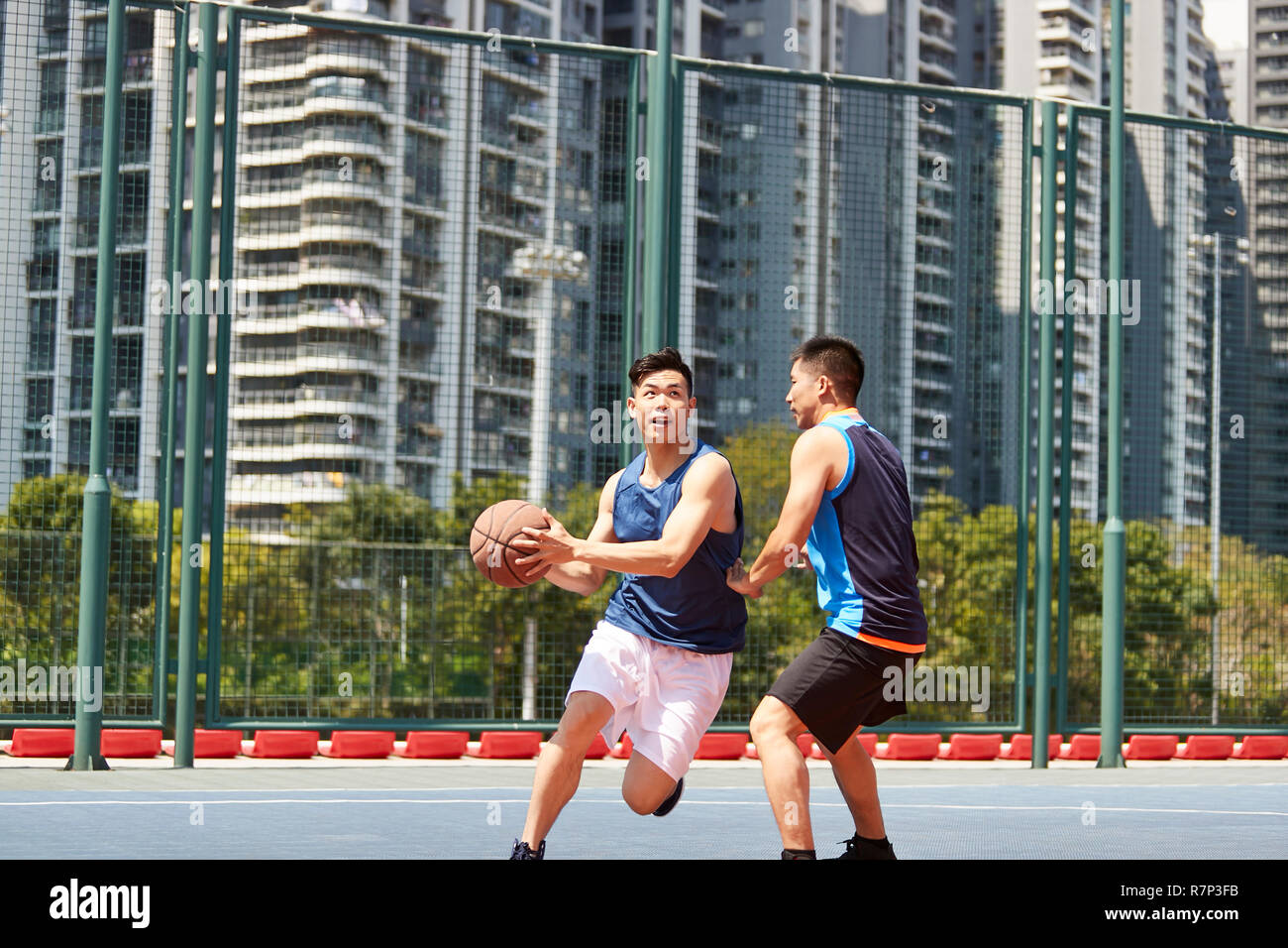 Deux jeunes joueurs de basket-ball asiatique jouant un sur une cour en plein air. Banque D'Images