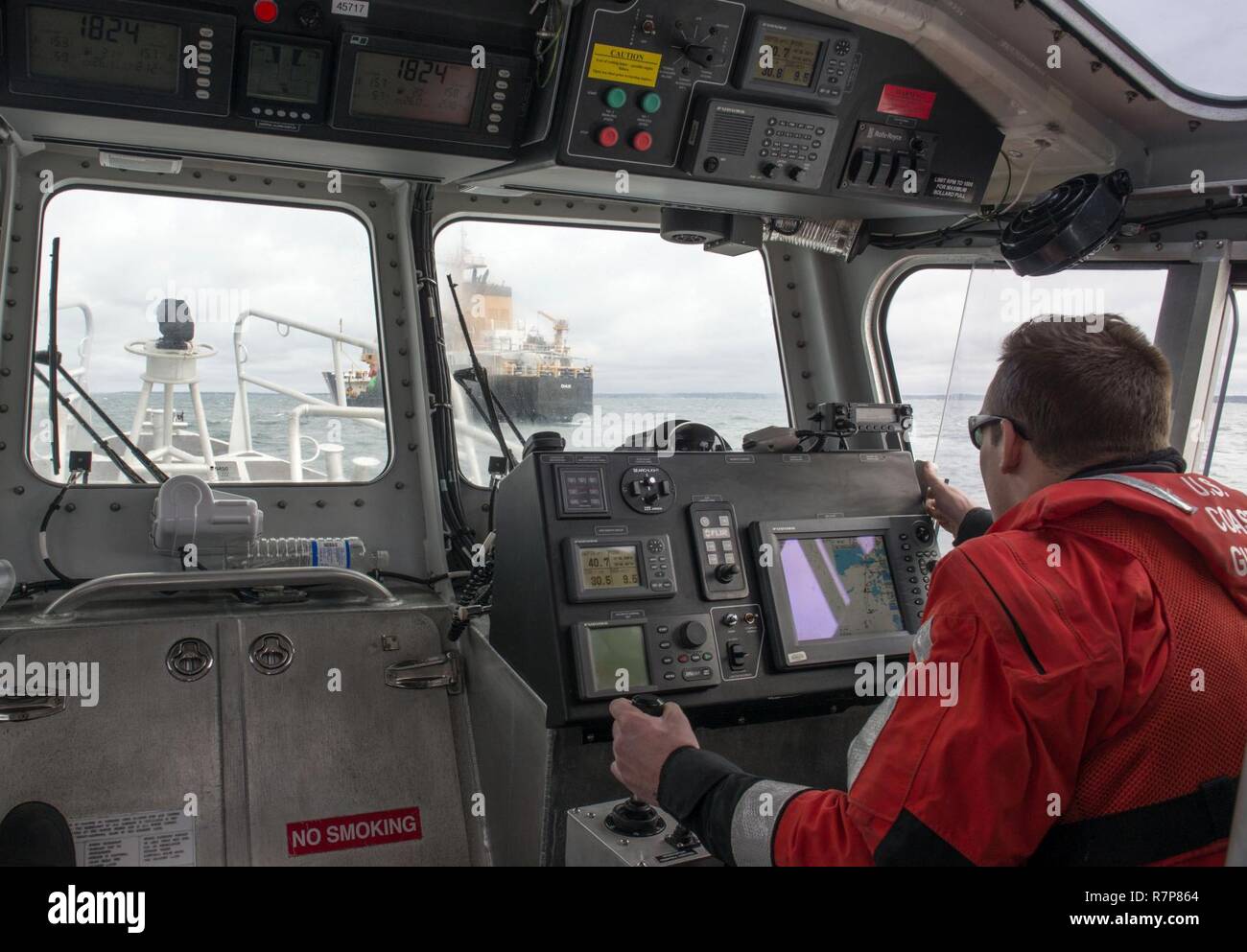 Maître de 3e classe Henry Wiley, un poste d'équipage de Woods Hole, regarde vers les garde-côte de chêne lors d'une patrouille à bord d'un bateau d'intervention de 45 pieds à Buzzards Bay, Massachusetts, le mercredi 29 mars, 2017. Gare la Woods Hole est une unité qui effectue des ports, voies navigables et la sécurité côtière, Recherche et Sauvetage, sécurité des bateaux de plaisance, des opérations et des ressources marines vivantes de l'application de la pêche dans son vignoble, Nantucket Sound, et Buzzards Bay. Banque D'Images