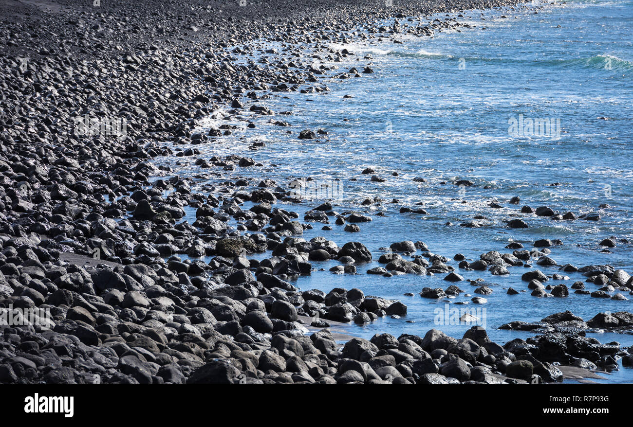 Pierre noire, plage et mer bleue. Banque D'Images
