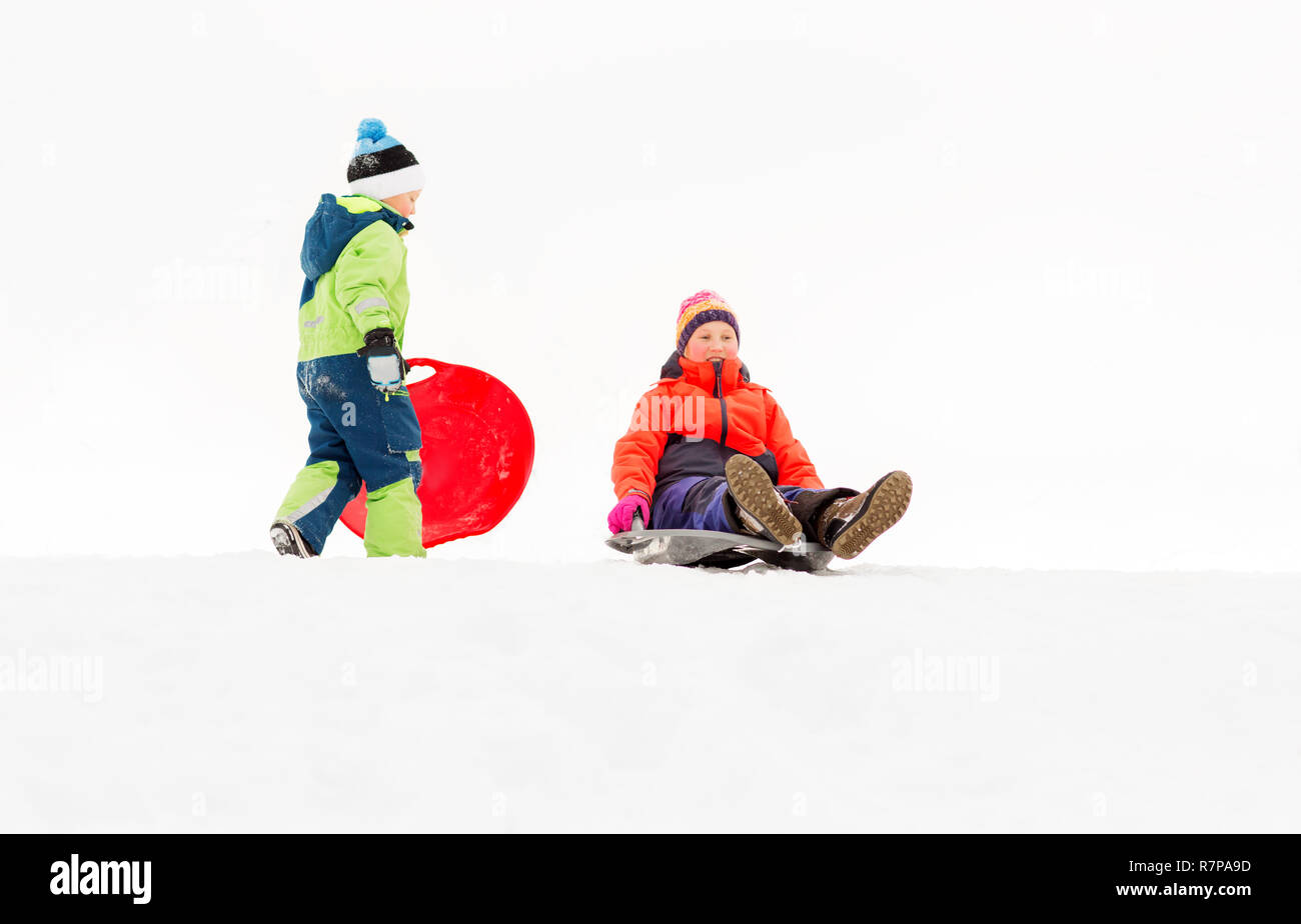 Happy kids sur des traîneaux glissant en bas de la colline en hiver Banque D'Images