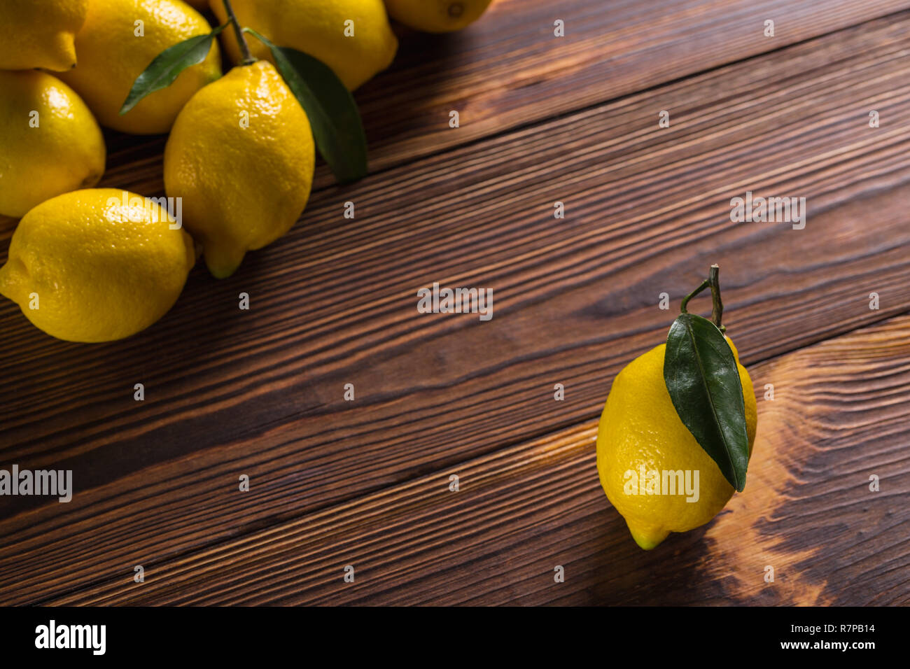 Citrons jaunes fraîches avec des feuilles se situent sur une table en bois. Banque D'Images