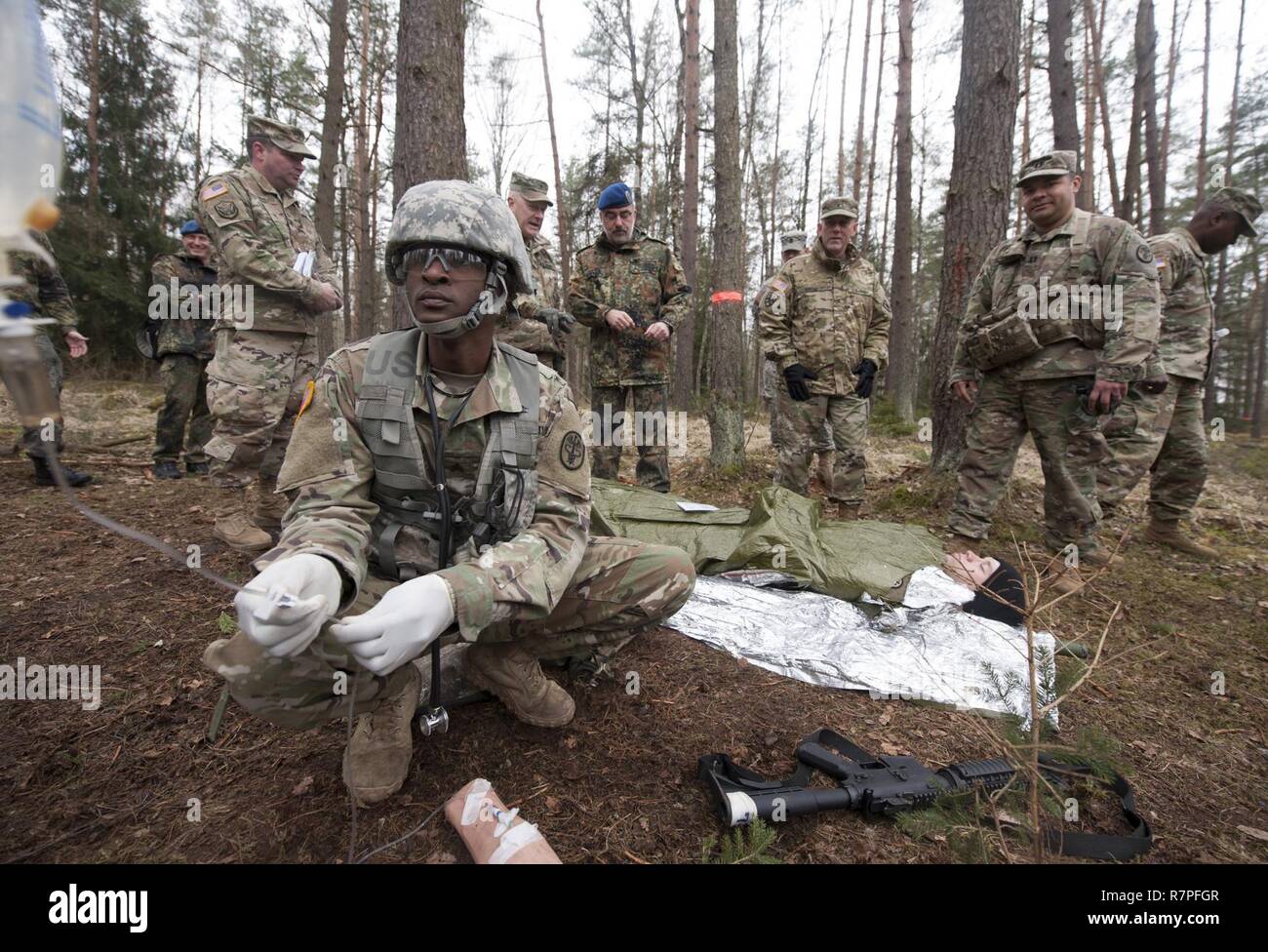 GRAFENWOEHR, Allemagne - visiteurs distingués de la Bundeswehr soutien médical opérationnel et Commande Commande de soutien du théâtre 21 Observer une démonstration lors d'un soldat de l'Armée américaine au cours d'une Europe de l'Armée américaine sur le terrain de l'évaluation d'experts médicaux d'un insigne à Grafenwoehr, Allemagne le 24 mars 2017. Environ 215 candidats de l'armée américaine et européenne de dix pays partenaires ont participé à l'évaluation semestrielle dans l'espoir d'atteindre l'armée américaine convoitée EFMB. Banque D'Images