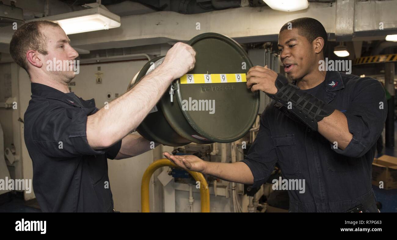 Le Golfe Arabique (23 mars 2017) Technicien en électronique 2e classe Tommy Klingel, gauche, et 2e classe Mécanicien Nicholas Pengelly bidons chimiques transfert à bord du porte-avions USS George H. W. Bush (CVN 77). GHWB est déployée dans la zone 5e flotte américaine des opérations à l'appui d'opérations de sécurité maritime visant à rassurer les alliés et les partenaires, et de préserver la liberté de navigation et la libre circulation du commerce dans la région. Banque D'Images