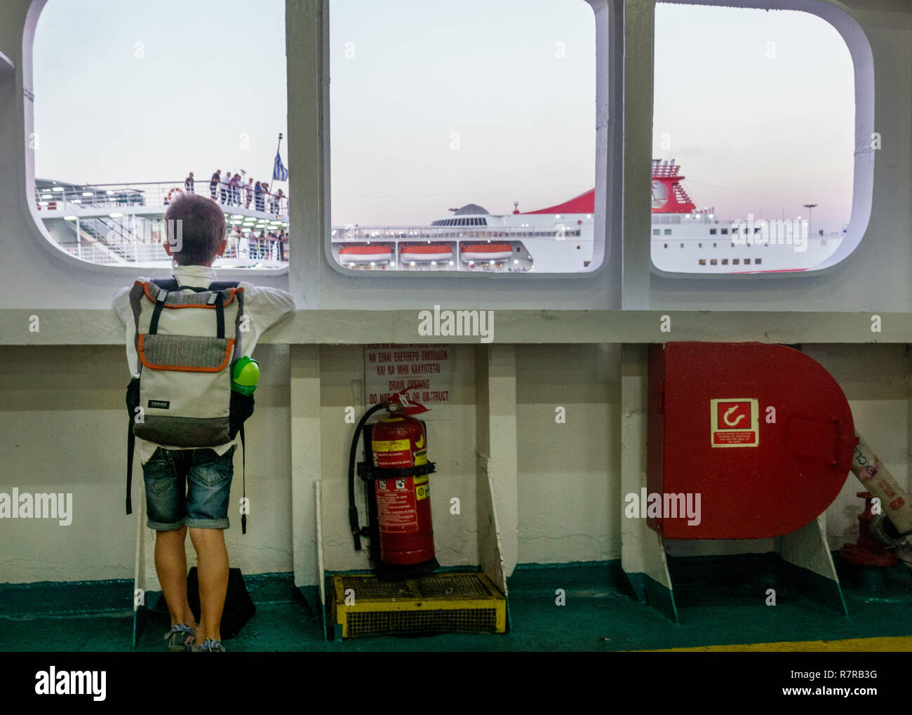 Boy looking at bateau de croisière à travers la vitre Banque D'Images
