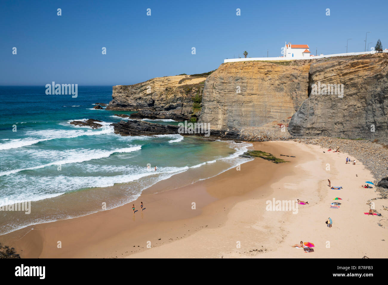 Falaise chapelle de Igreja de Nossa Senhora do Mar avec les vagues de l'Atlantique sur la plage de sable dans le soleil du matin à Zambujeira do Mar Banque D'Images