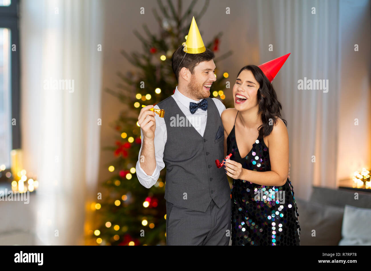 Couple avec party blowers s'amusant à Noël Banque D'Images