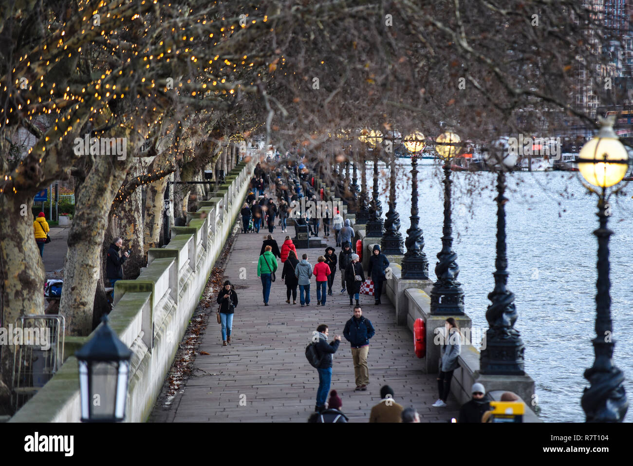 Albert Embankment le long de la rivière Thames à Lambeth, Londres en soirée avec les lumières d'arbre de Noël et de l'esturgeon lampadaires allumés. Les randonneurs, touristes Banque D'Images