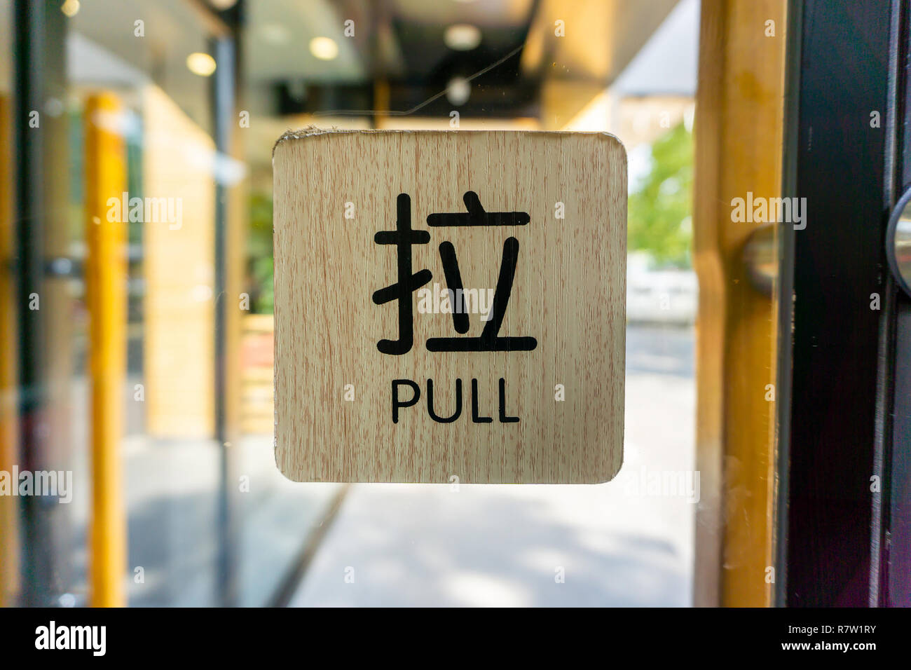 Pull noir signe en anglais et en chinois sur un fond de bois sur la porte en verre Banque D'Images