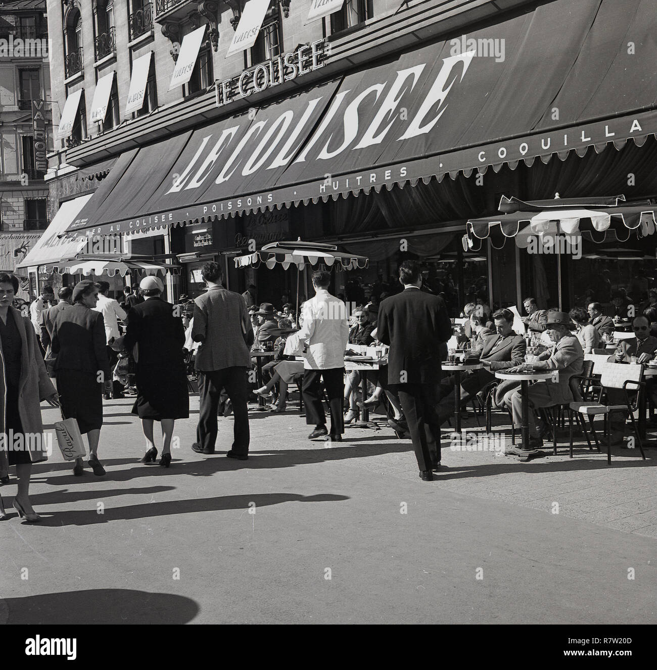 Années 1950, historiques, les gens assis dans le bar en plein air, sur le trottoir devant le restaurant le Colisee, par la célèbre avenue des Champs-Elysées, Paris, France, Banque D'Images