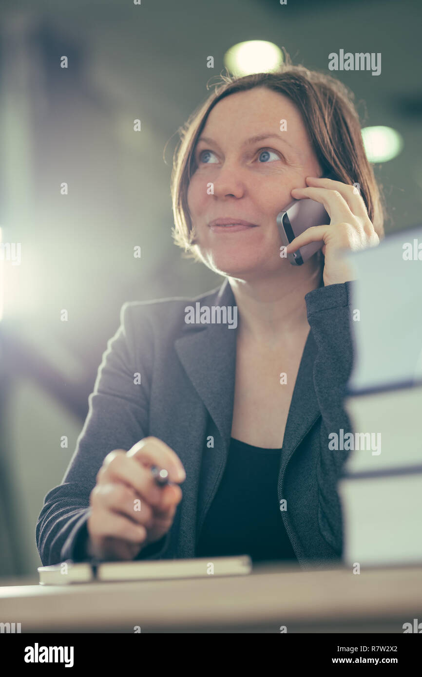 Happy smiling businesswoman talking on mobile phone depuis son bureau 24, selective focus Banque D'Images
