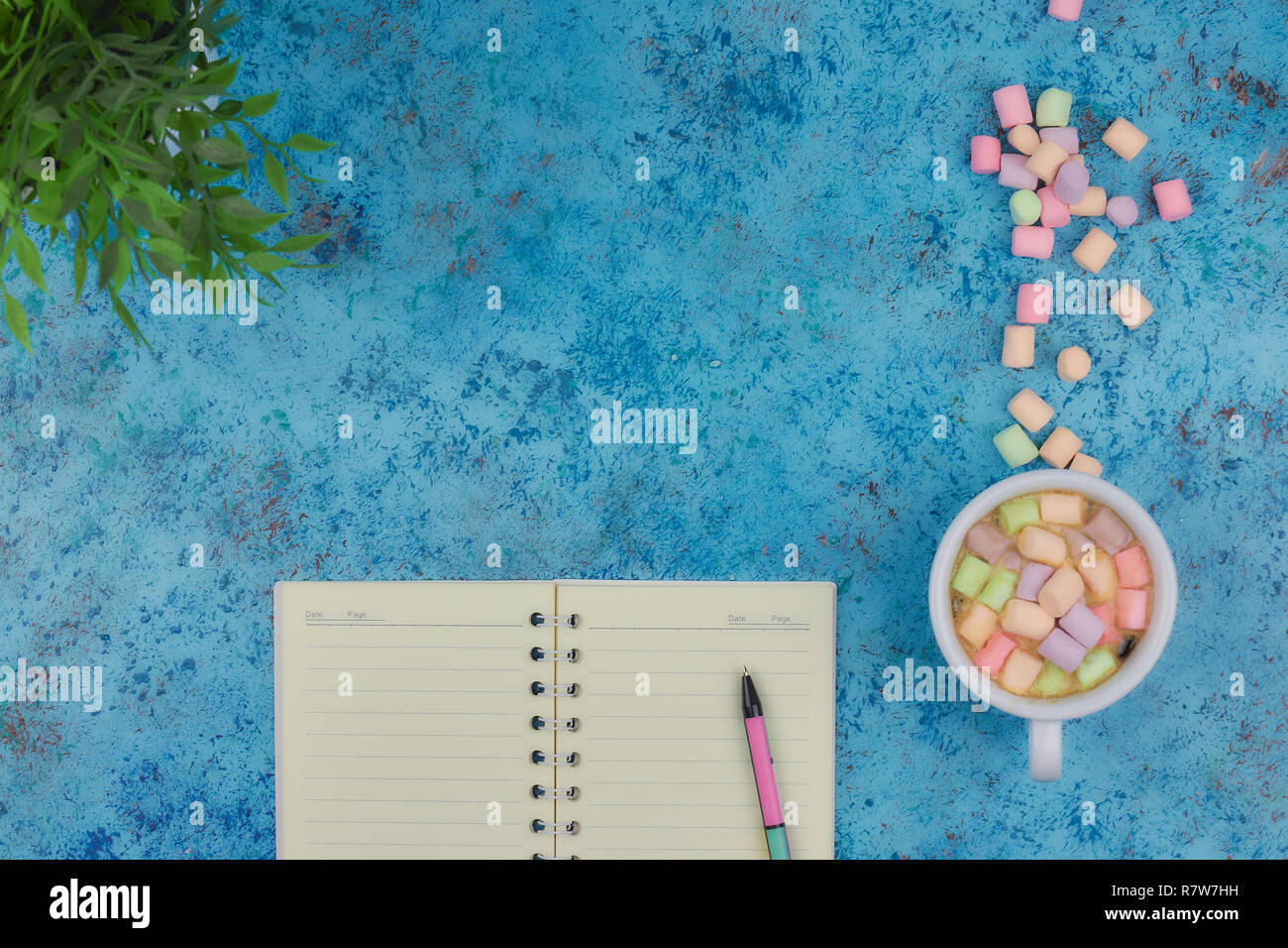 Tasse à café et les guimauves, vierge ouvrir bloc-notes avec stylo sur résumé fond bleu. Vue d'en haut. Télévision immersive. espace pour texte. Banque D'Images