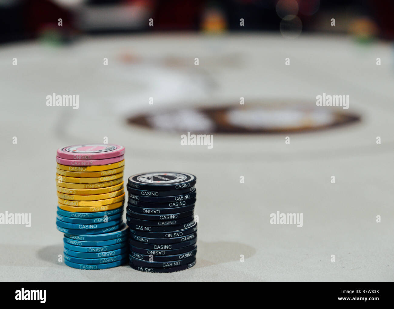 Deux piles de jetons de poker avec table de poker de flou artistique en arrière-plan. Banque D'Images