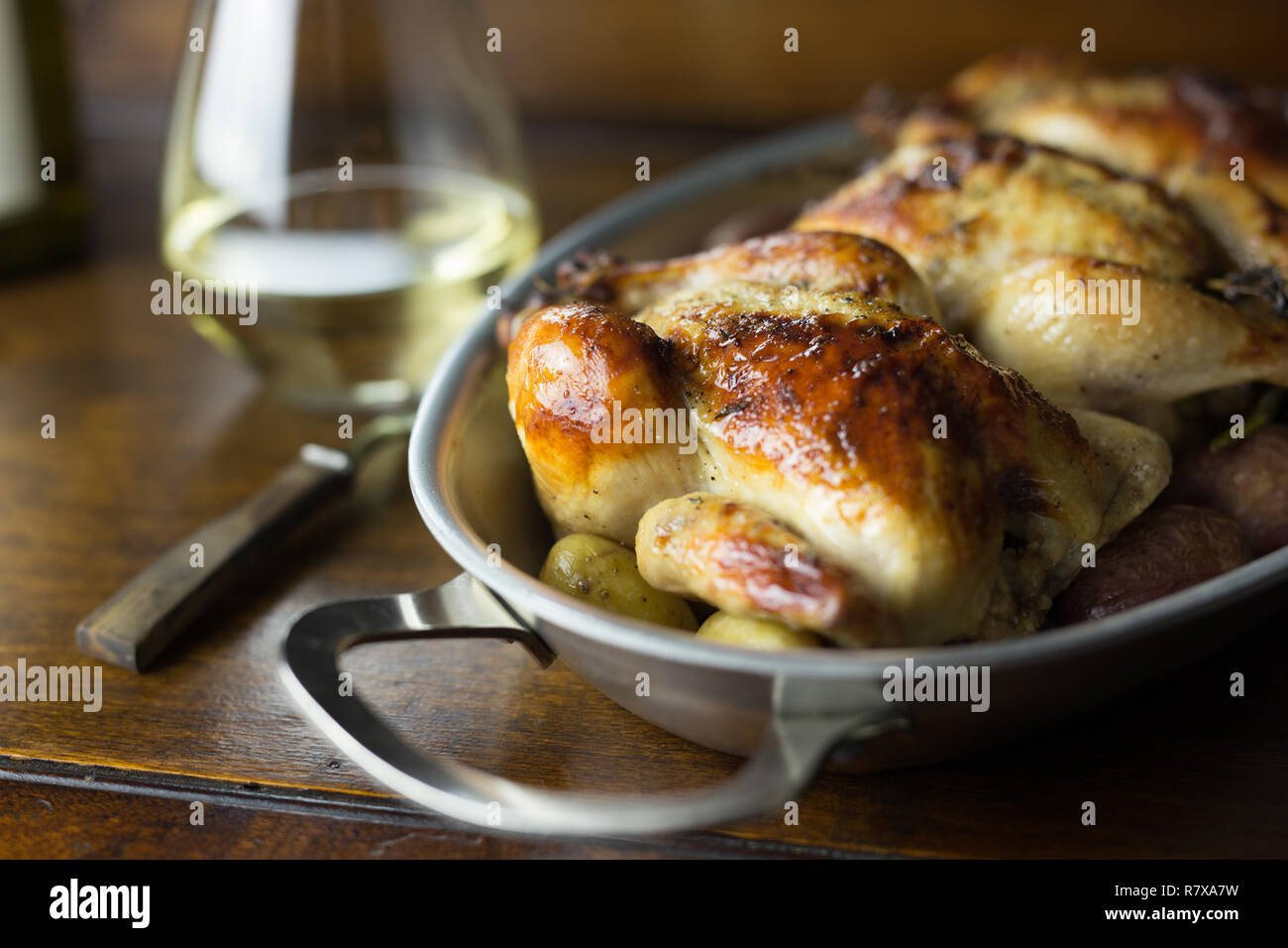 Trois poulets de Cornouailles dans un plat allant au four avec des pommes de terre nouvelles. Close up shot. Banque D'Images