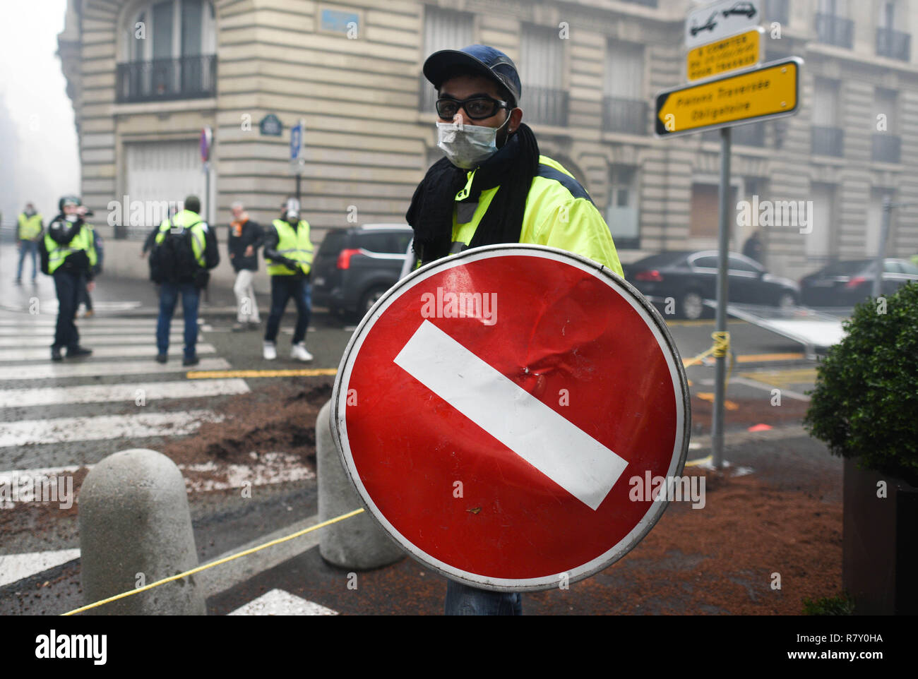 Décembre 01, 2018 - Paris, France : un gilet jaune manifestant utilise un  panneau routier comme un bouclier dans une rue près de l'avenue des  Champs-Élysées, où plusieurs véhicules ont été incendiés.