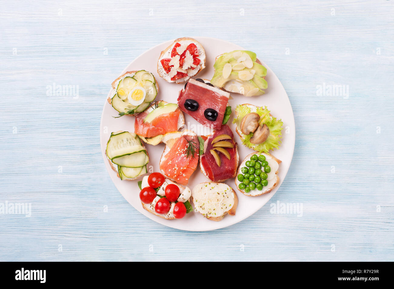 De savoureux canapés de saumon fumé, concombre, cerisier, de la mozzarella, les oeufs, les champignons, les olives, l'avocat, les amandes servi sur une assiette. Banque D'Images