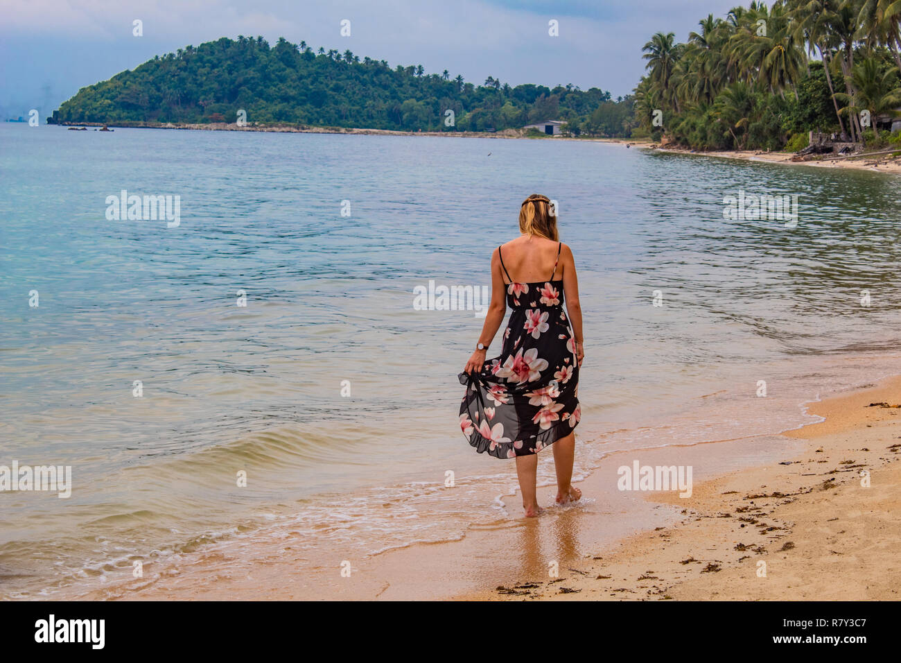 Femme avec de longues balades sur la plage robe d'été Banque D'Images