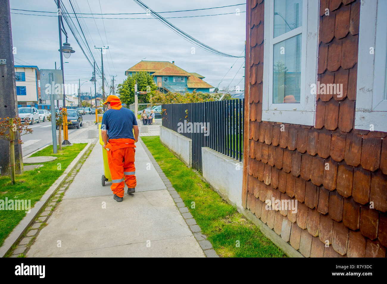 PUERTO VARAS, CHILI, septembre, 23, 2018 : homme non identifié portant des uniformes orange et de marche dans le trottoir près d'un bâtiment en bois situé à Puerto Varas au Chili Banque D'Images