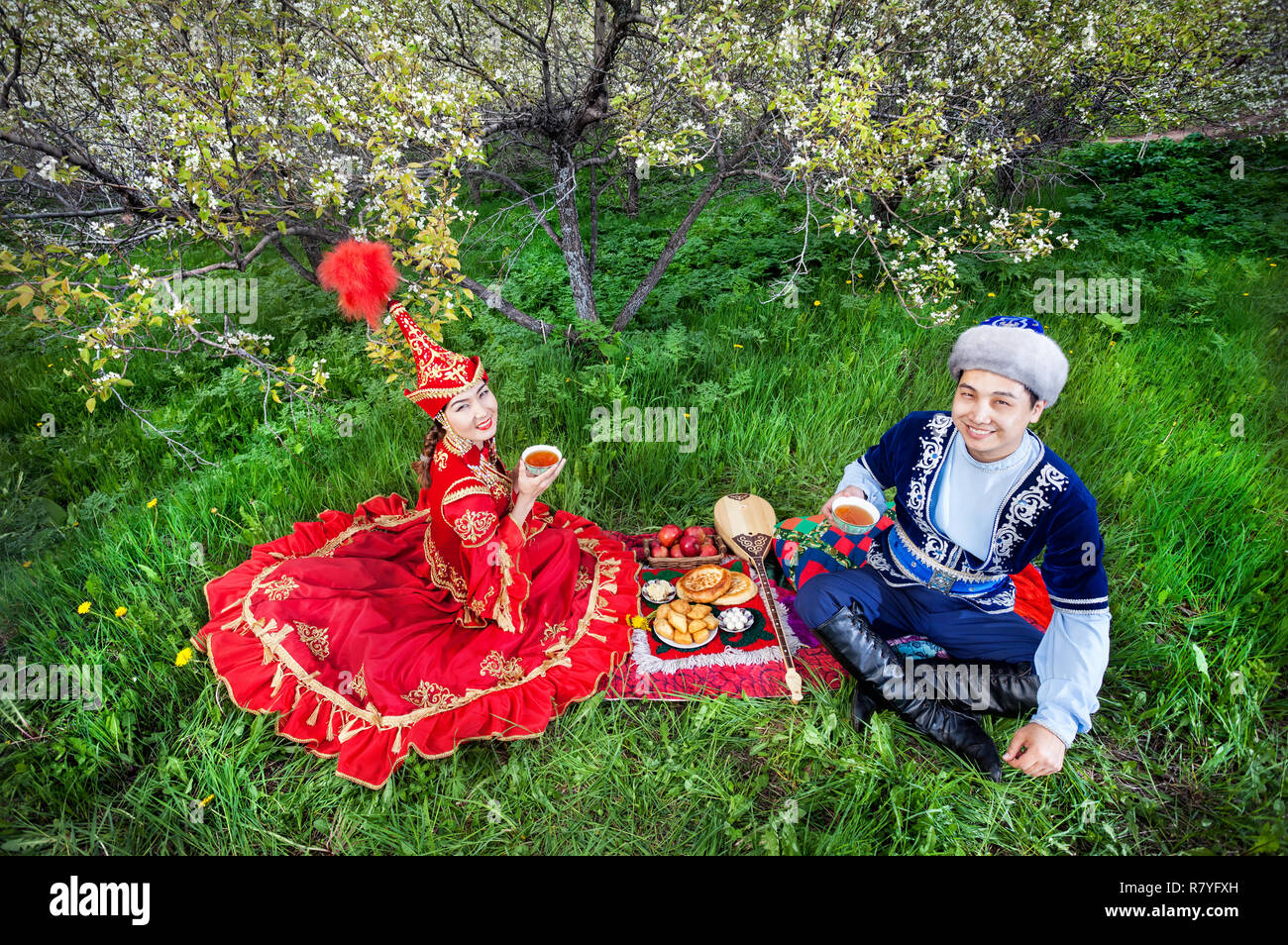 Couple Kazakh boire le thé sur l'herbe verte dans le jardin d'apple d'Almaty, Kazakhstan, en Asie centrale Banque D'Images