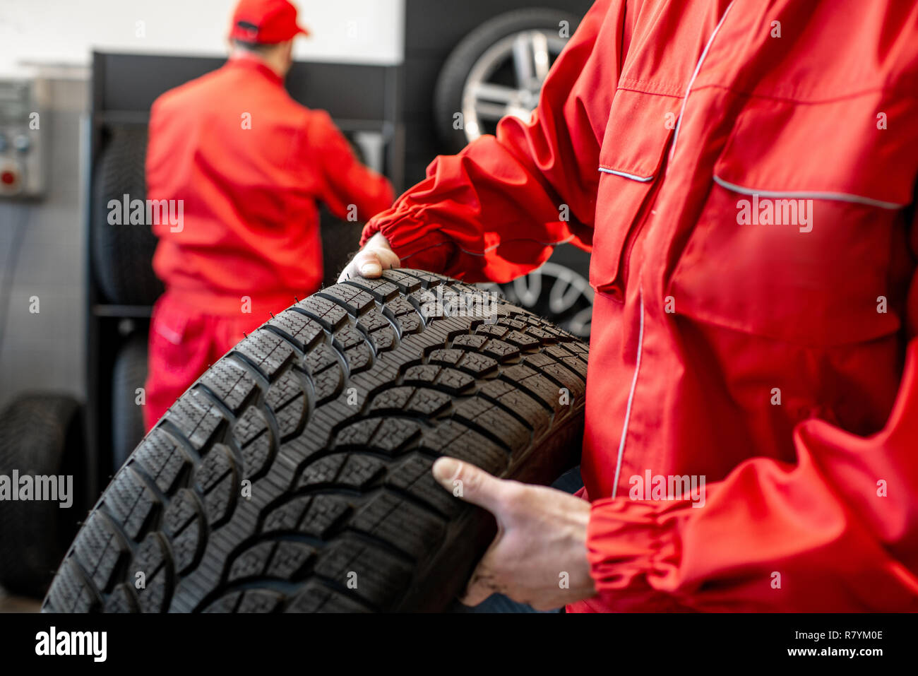 Travailleur dans l'exécution uniforme des pneus neufs à la location de service ou magasin, close-up view Banque D'Images