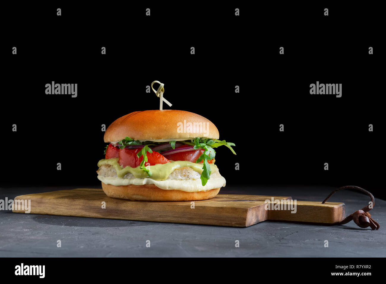 Burger de boeuf grillé savoureux avec de la laitue, le fromage et l'oignon servis sur une planche à découper avec copyspace Banque D'Images