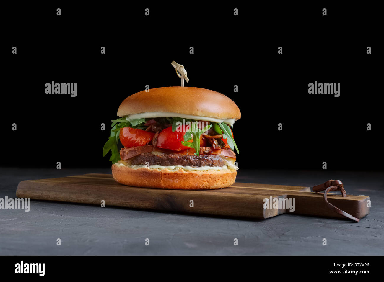 Burger de boeuf grillé savoureux avec de la laitue, le fromage et l'oignon servis sur une planche à découper avec copyspace Banque D'Images