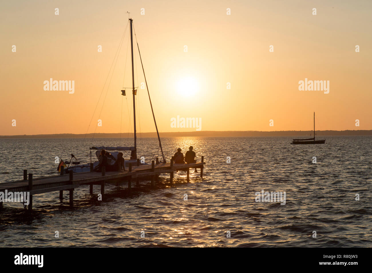 Jetty et historique (bateaux à voile Auswanderer) sur le lac Steinhude au coucher du soleil. Basse-saxe, Allemagne Banque D'Images