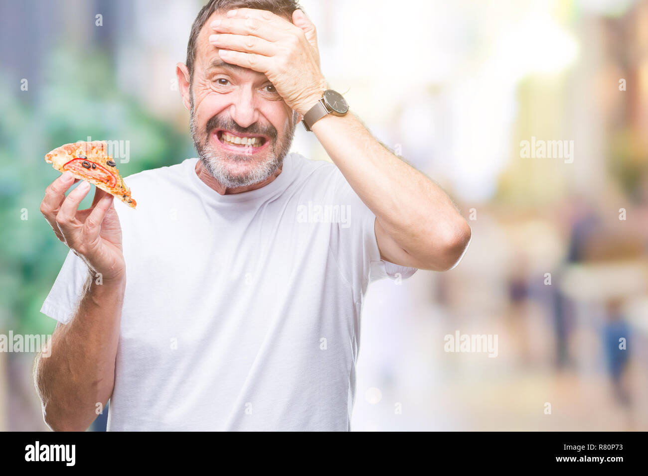L'âge moyen des cadres supérieurs des man eating pizza slice sur fond isolé a souligné avec la main sur la tête, choqué par la honte et la surprise face, en colère et fr Banque D'Images