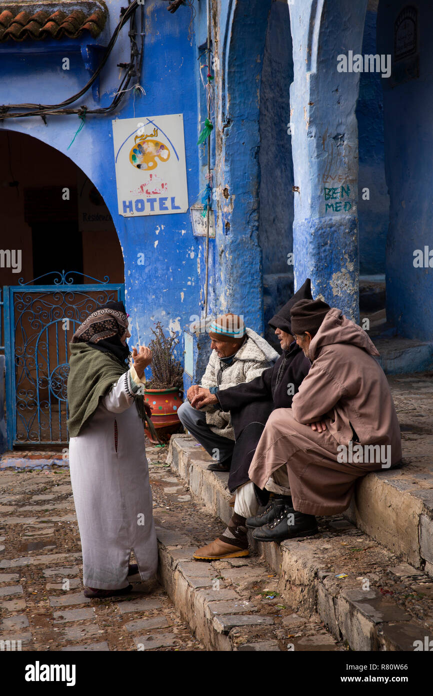 Le Maroc, Chefchaouen, ville bleue, Place El Mazjen, de vieux hommes en djellabas sam parler aux femme Banque D'Images